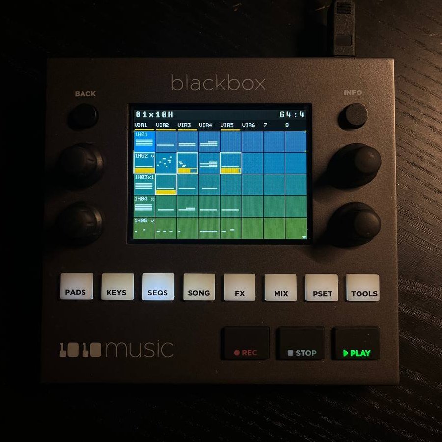 1010music Blackbox on a dark desk, its screen showing the modded SEQS clip launcher with named columns and coloured clips