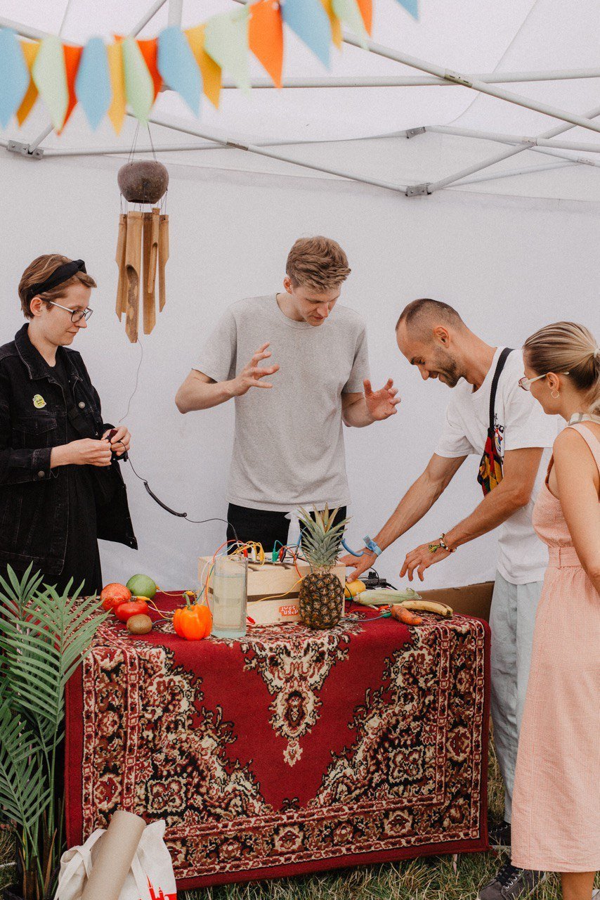 People playing the fruit installation on a table with a red carpet